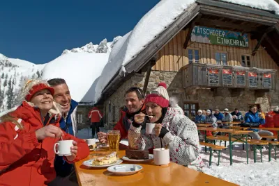 Skiërs met koffie en gebak op een zonnig terras van een berghut