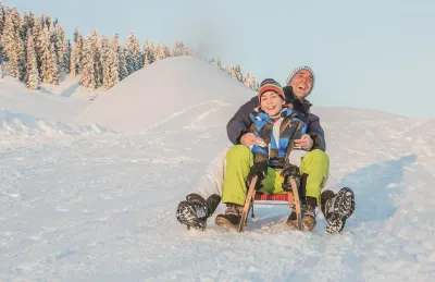 Een lachende vader en zoon samen op een houten slee